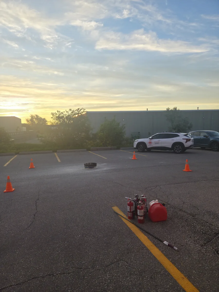 Portable extinguishers and a training pan inside a coned outdoor practice area.